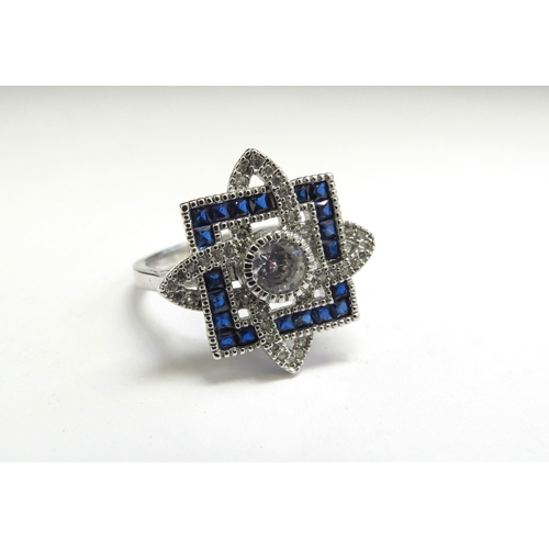 9077 - A dress ring with centre white stone in halo of blue stones with white stone set swirls, stamped 925... 