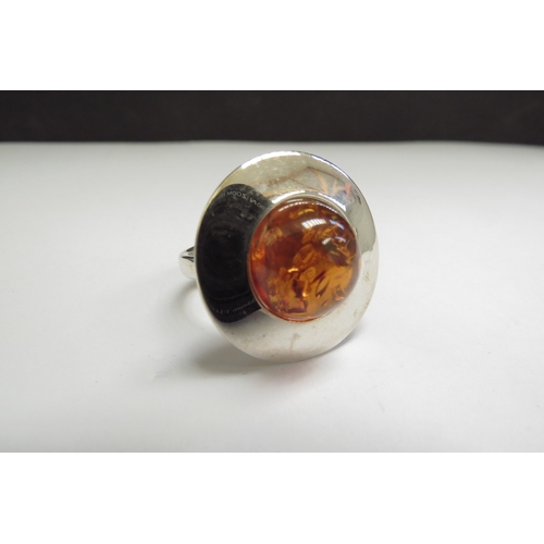 9072 - An amber dress ring of circular form, adjustable shank stamped 925. Size R+, 9.4g