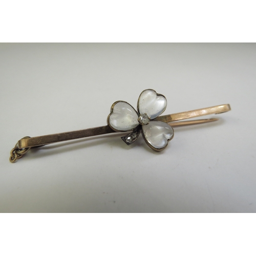 9110 - A gold bar brooch with a moonstone heart shaped clover, with central old cut diamonds with diamond s... 