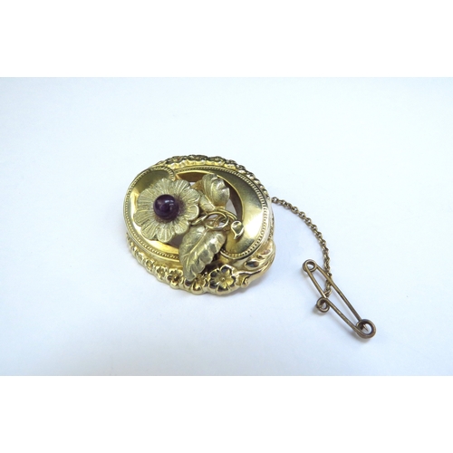 9188 - An unmarked gold brooch the centre as a flower with central amethyst in ornate frame with floral dec... 