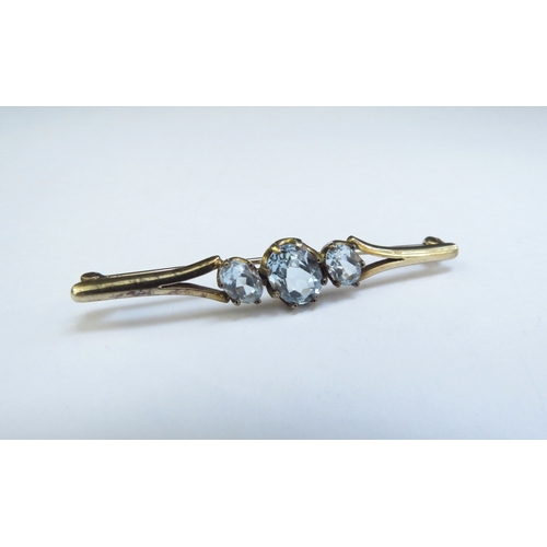 9164 - A 9ct gold bar brooch set with three pale blue topaz, 5cm long, 3.3g  (R)  £25