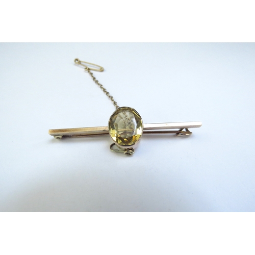 9125 - An unmarked gold bar brooch with an oval citrine, 5cm long, 4.5g  (R)  £75