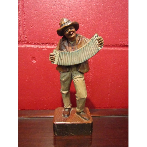 4126 - A carved wooden figure of a Thyrdian man playing an accordian, 26cm height