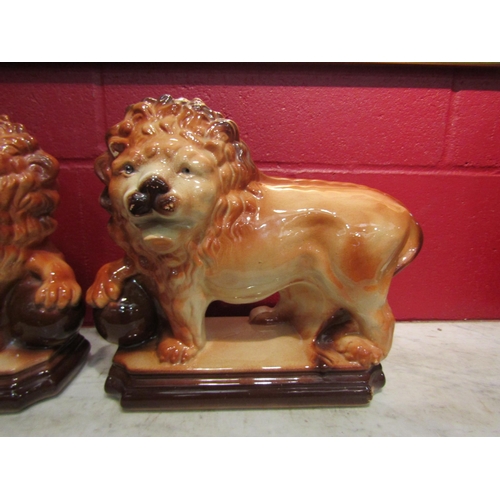 4155 - A pair of Staffordshire standing lion figures, one missing eye, 33cm long x 29cm tall