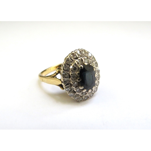 9261 - A sapphire and diamond cluster ring, central oval sapphire framed by two rows of diamonds, stamped 1... 