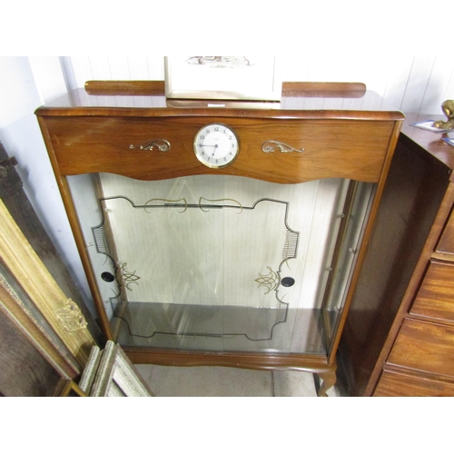 2103 - A 1940's walnut glass door shelving unit with Smith's clock in the centre