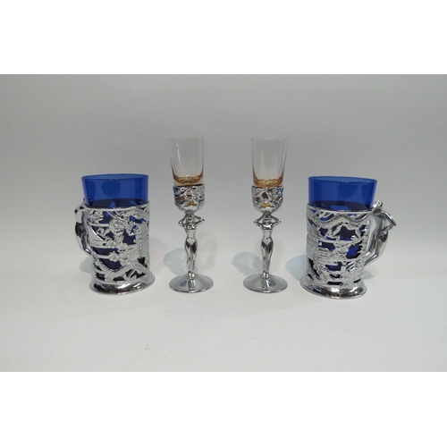 4452 - Two Oriental tankards with blue glass liners decorated with nude lady handles together with two shot... 