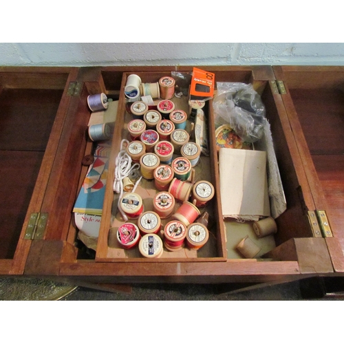 1040 - A teak sewing table with twin lift-lid, together with a brass top occasional table (2)