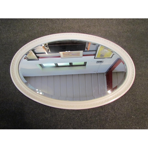 1084 - A painted white oval wall mirror with bevelled glass, 60cm x 90cm total