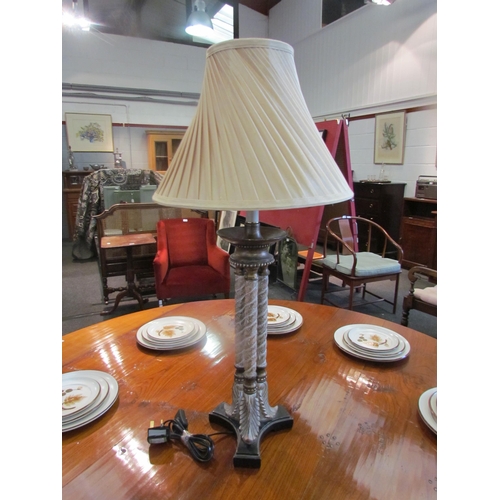 1095 - A black and gilt three column table lamp with cream pleated shade, 83cm tall