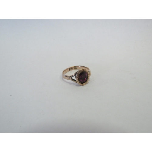 1304 - A gold ring set with an oval garnet, repaired, stamped 18ct. Size I, 2.1g  (C)