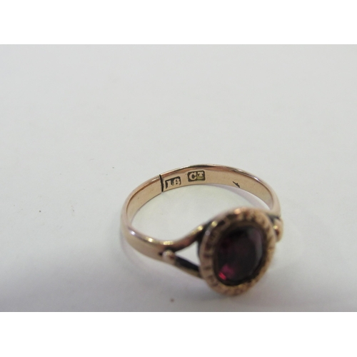 1304 - A gold ring set with an oval garnet, repaired, stamped 18ct. Size I, 2.1g  (C)