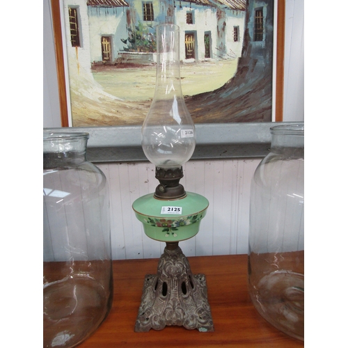 2125 - A Victorian oil lamp with green glass sump over painted with flowers, cast iron base