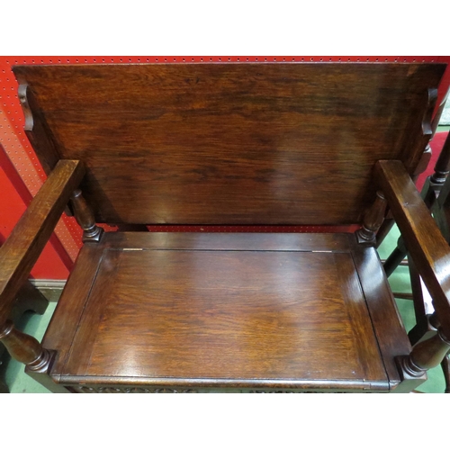 4099 - A monk's bench with table top and box seat, the hinged seat and turned supports over a carved linen-... 