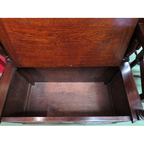 4099 - A monk's bench with table top and box seat, the hinged seat and turned supports over a carved linen-... 