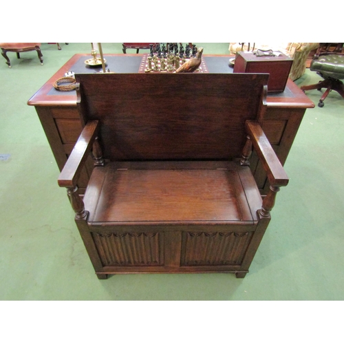 4099 - A monk's bench with table top and box seat, the hinged seat and turned supports over a carved linen-... 