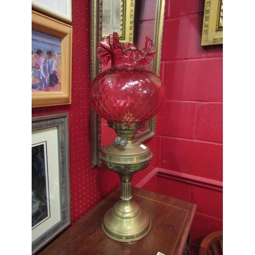 4111 - A brass based oil lamp with red frilled shade