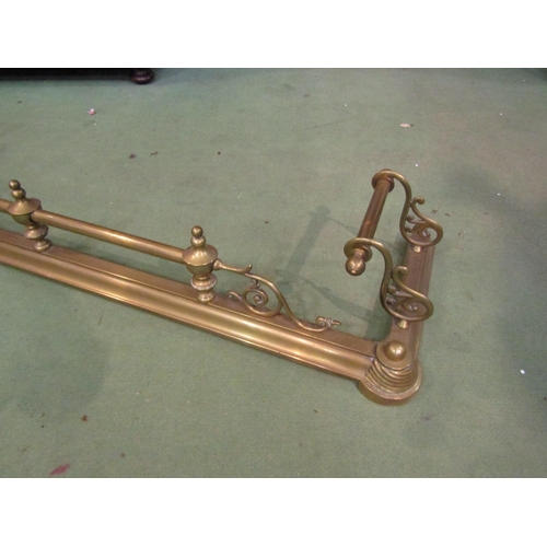 4146 - An ornate brass fire fender with scrolled supports and finials, 130cm long x 36cm deep   (R) £20