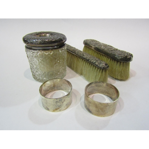 4315 - Two silver napkin rings, a silver topped dressing table pot, and two silver topped brushes (5)