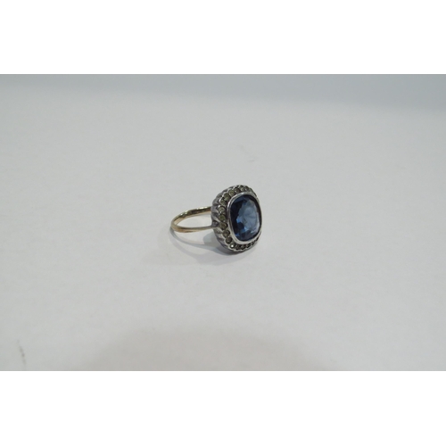 4390 - A costume ring set with large blue stone framed by clear stones, unmarked, size L, 3.2g