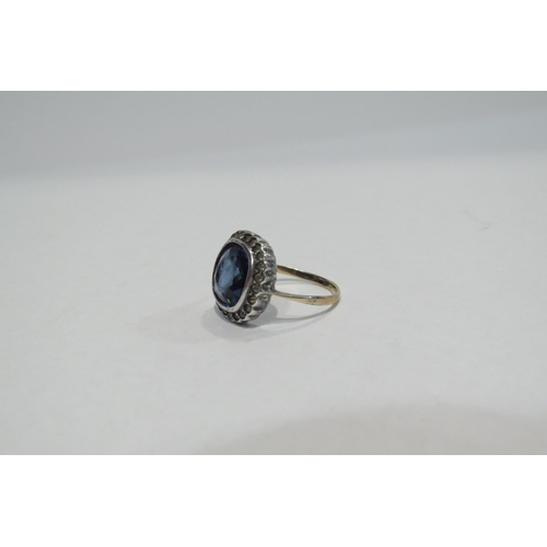 4390 - A costume ring set with large blue stone framed by clear stones, unmarked, size L, 3.2g