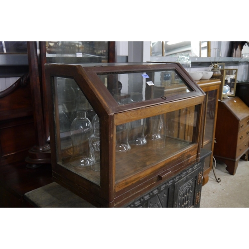 2126 - A table top glazed shop cabinet with lift top and lower drawer