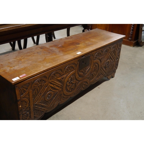 2215 - A 19th Century six plank coffer with highly ornate carved front, 129cm long, legs a/f