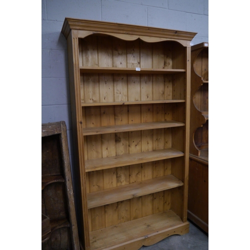 2328 - A pine floor standing bookcase, shaped cornice, five shelves, shaped base