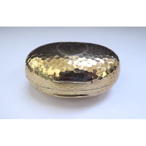 6438 - An Albert Barker Ltd silver gilt hinged ovoid shaped box with hammered decoration, circular cartouch... 