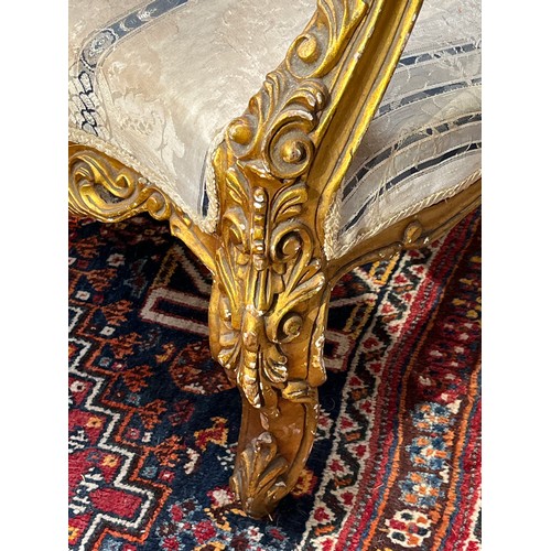 6044 - An early 20th Century French giltwood three piece suite with silk upholstery, some gilding is distre... 