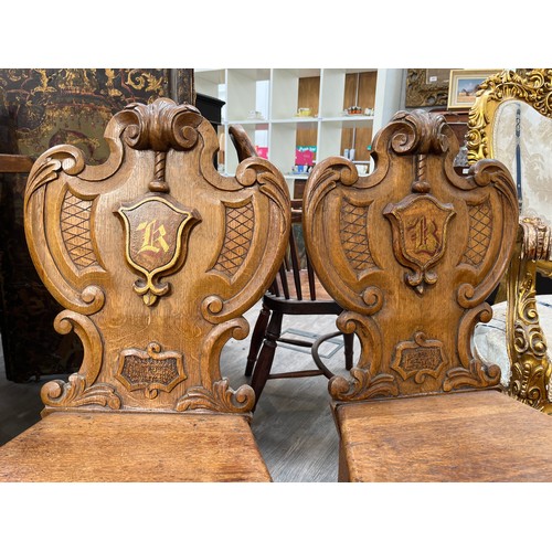 6045 - A pair of late Victorian oak heraldic shield back hall chairs, 84cm x 45cm wide