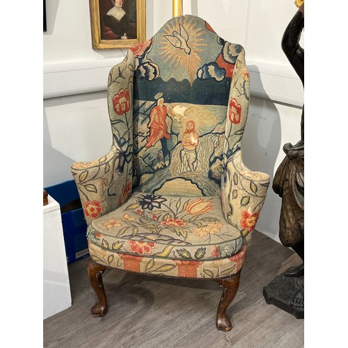 6092 - An early to mid 18th century wingback armchair with holy needlepoint upholstery, well worn, thread b... 