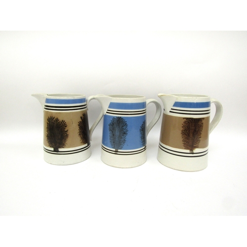 6056 - Three Quart Mocha ware jugs, one blue and two pale brown, one with crack to spout, 16cm talk