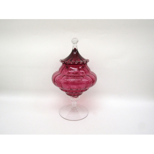 6119 - A cranberry glass lidded jar on pedestal base, one piece of prunt work damaged, 33cm tall