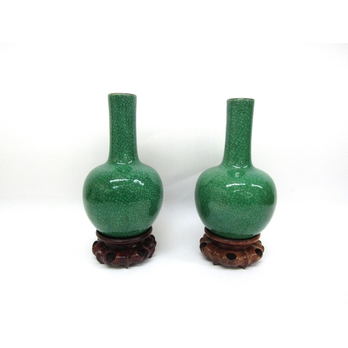 6345 - A pair of Chinese apple-green crackle-glazed bottle vases on carved wooden stands, label to inside o... 