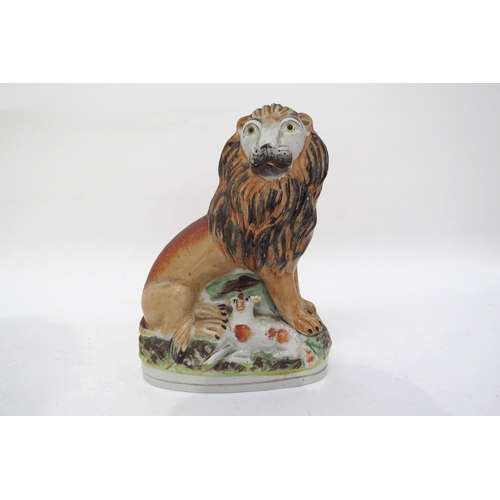 6310 - A 19th Century Staffordshire seated lion with lambs sat between its feet, 17cm tall x 12.5cm tall