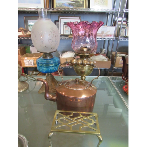 1457 - An oil lamp with ornate cast base, a brass oil lamp, copper kettle and brass trivet (4)