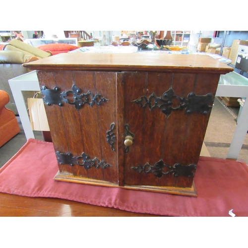 1469 - An oak table-top collectors' cabinet with iron work to doors, 38cm tall x 45cm wide x 21cm deep