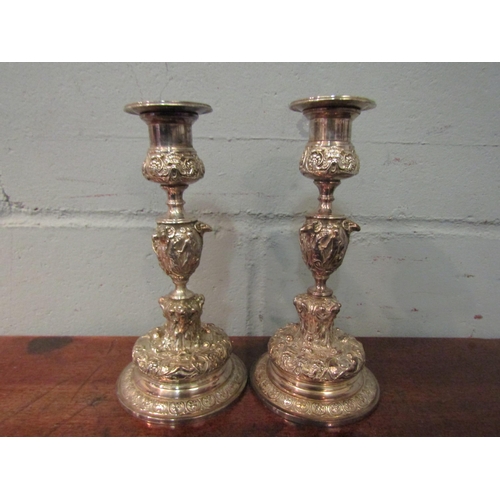 1047 - A pair of silver plated candlesticks, the stems decorated with rams masks and figural panels, 18.5cm... 