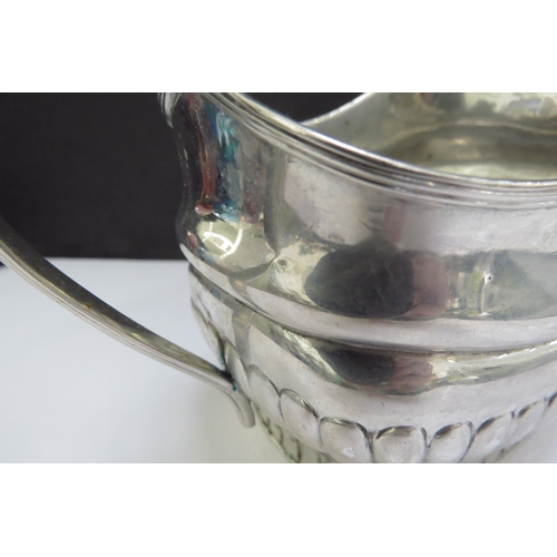 6485 - An early 19th Century Irish silver milk jug, stirrup handle and fluted detail, sea creature designed... 