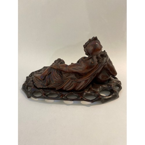 6338 - A Chinese carved figure of an Immortal resting on a carved bespoke base, 21cm x 41.5cm