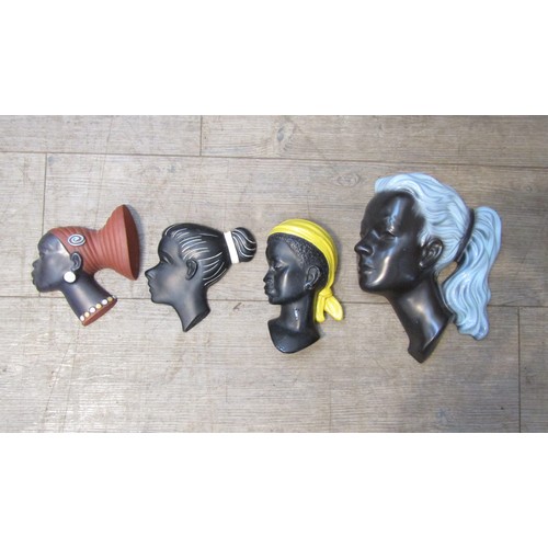 9106 - Four painted female head wall plaques in plaster and ceramic, various designs. Largest 26cm high