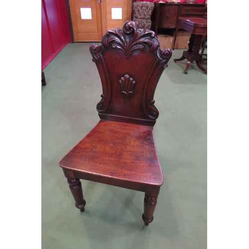 4002 - A circa 1840 mahogany hall chair, the carved back rest over turned and tapering fore legs, 91cm long... 