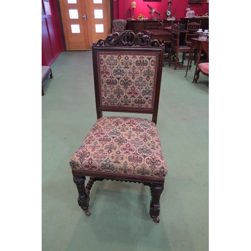 4106 - A Victorian carved walnut chair with carved fore legs on ceramic castors united by a bobbin turned 