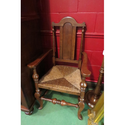 4139 - An 18th Century revival oak armchair, the broad arms over a rush seat on turned and cabriole fore le... 