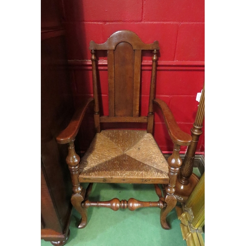 4139 - An 18th Century revival oak armchair, the broad arms over a rush seat on turned and cabriole fore le... 