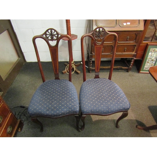 1143 - A pair of Edwardian crossbanded mahogany chairs with carved decoration and blue upholstery