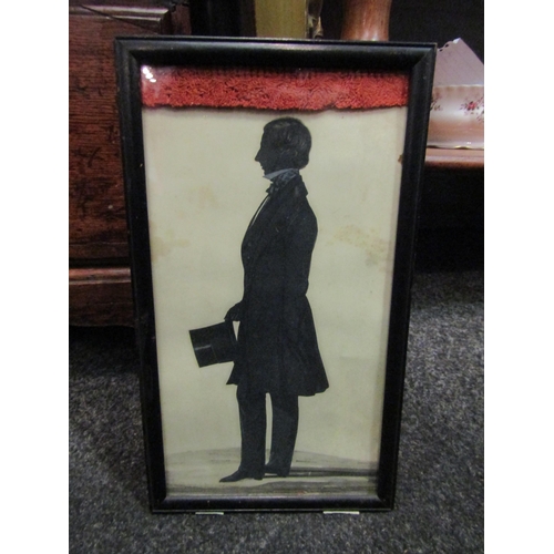 1087 - A full silhouette depicting a Victorian gent with frock coat attire holding a top hat, framed and gl... 