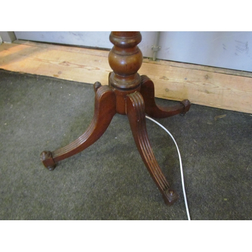 1004 - A 20th Century turned mahogany standard lamp on quatreform base with pleated shade