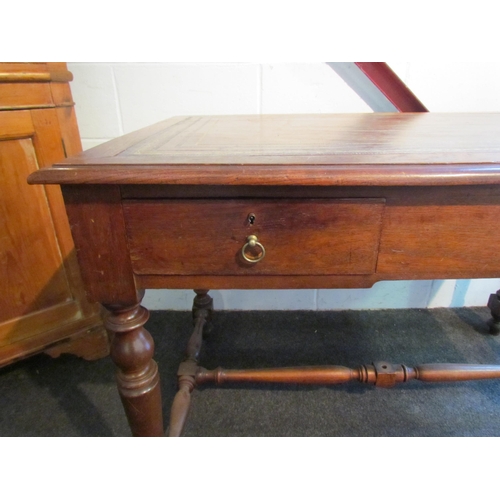 1008 - An early 20th Century desk, the tooled leather top over two frieze drawers, turned supports joined b... 